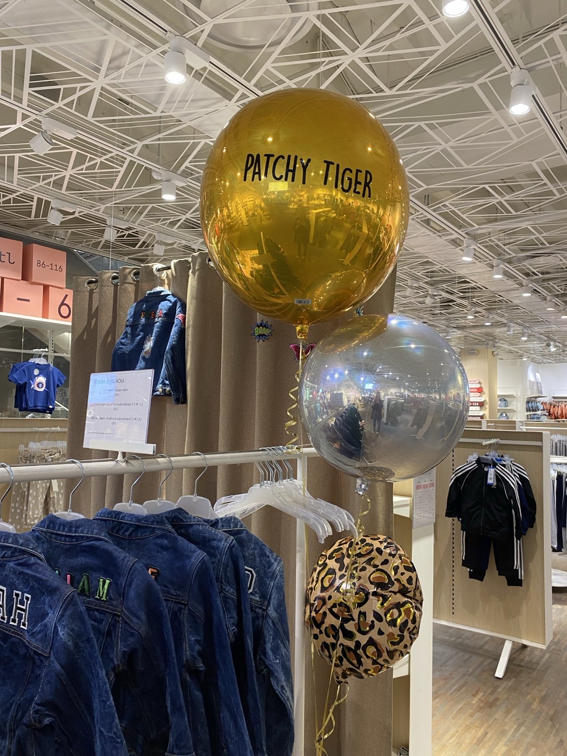 Gold Patchy Tiger balloon above a rail of personalised denim jackets